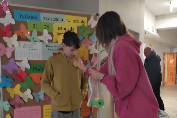 Pani przyklejająca kolorową buźkę uczniowi