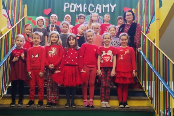 Uczniowie klas 1 przy napisie Pomagamy
