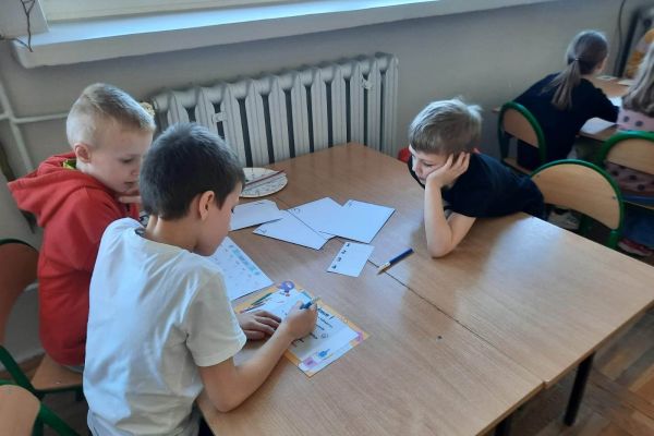 Dzieci rozwiązują zadania przy stolikach