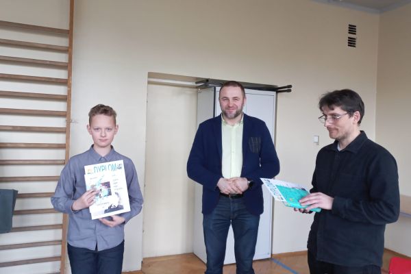 Adam odbiera dyplom i nagrodę