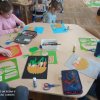 Dzieci_siedza_przy_stolikach_wykonuja_prace_plastyczna